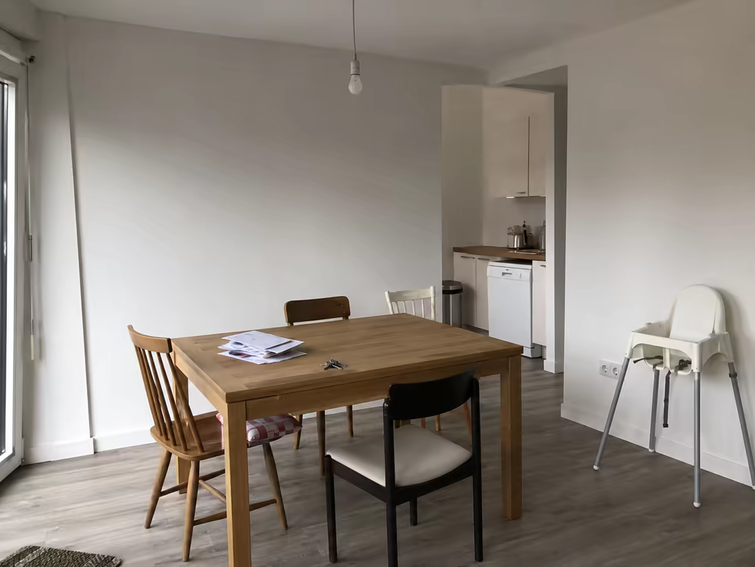 A bland dining area with mismatched chairs and a bare bulb