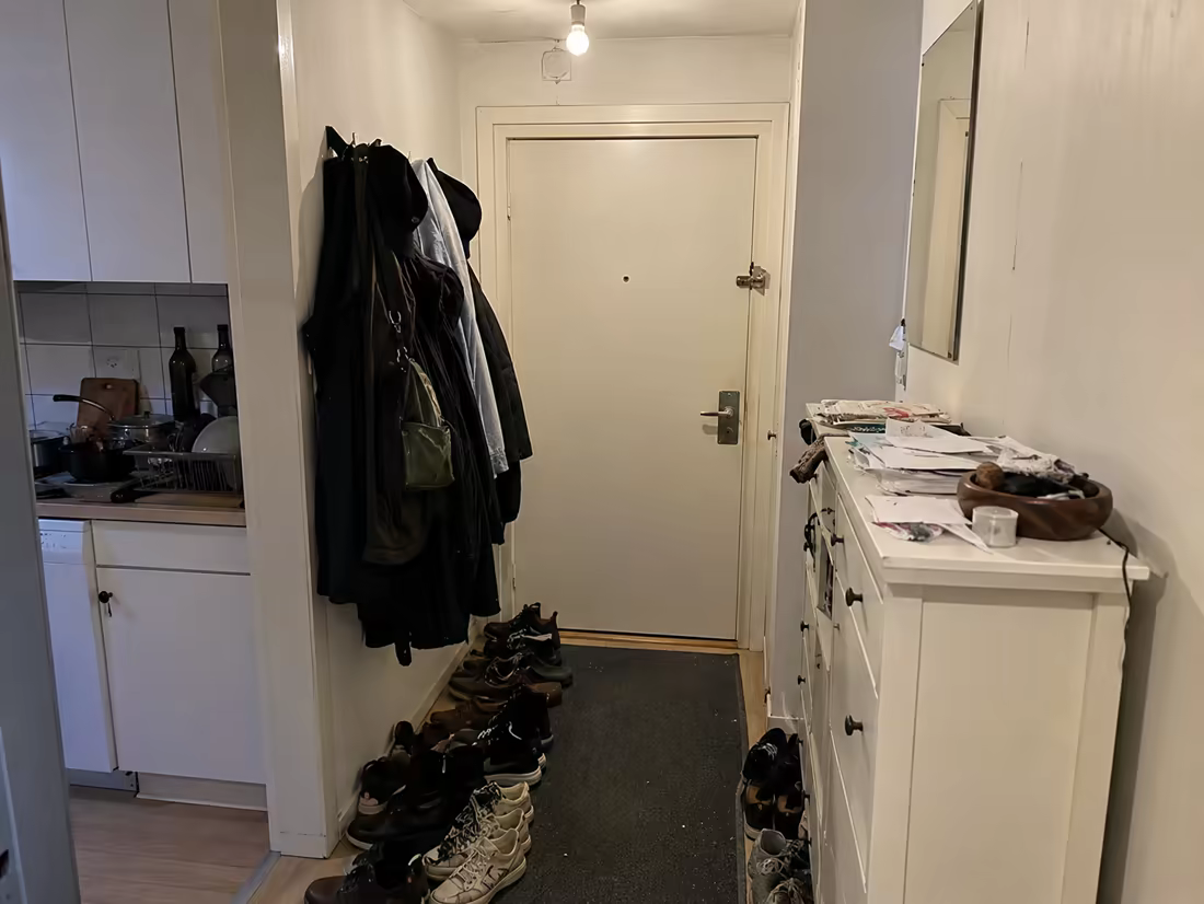 A cluttered entryway with piled shoes and overloaded coat hooks