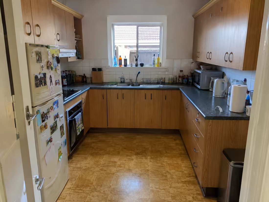 A dated kitchen with oak-laminate cabinets and cluttered counters